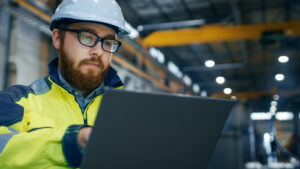 Industrial,engineer,in,hard,hat,wearing,safety,jacket,uses,touchscreen